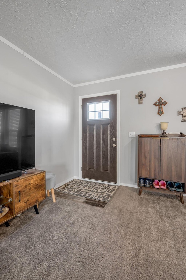 carpeted entryway with ornamental molding and a textured ceiling