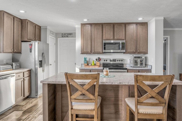 kitchen featuring a breakfast bar area, a kitchen island, light hardwood / wood-style floors, and appliances with stainless steel finishes