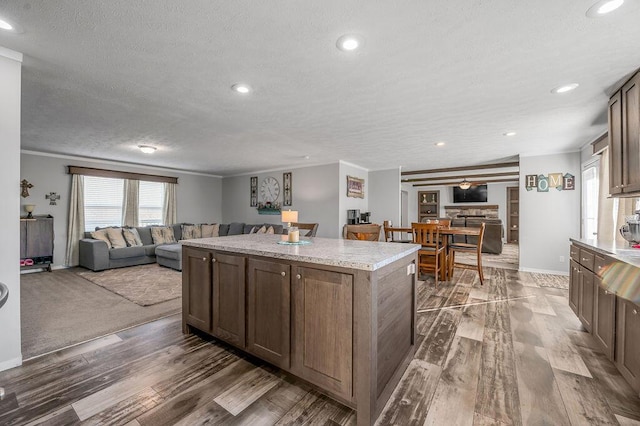 kitchen featuring dark hardwood / wood-style flooring, a center island, a textured ceiling, and crown molding