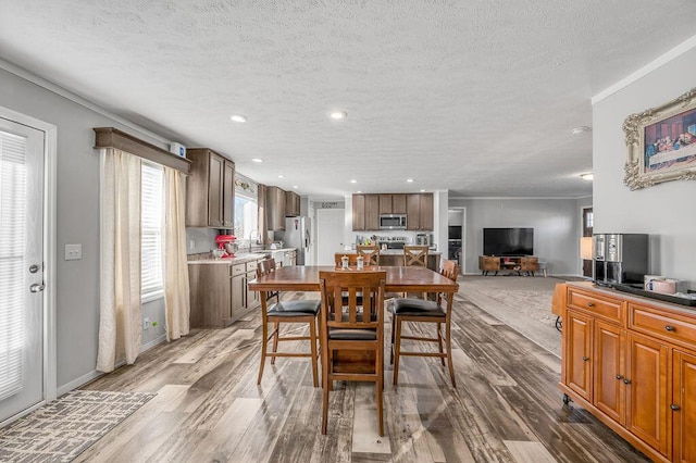 dining area featuring sink, wood-type flooring, and a textured ceiling