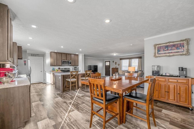 dining room with a textured ceiling, ornamental molding, sink, and light hardwood / wood-style flooring