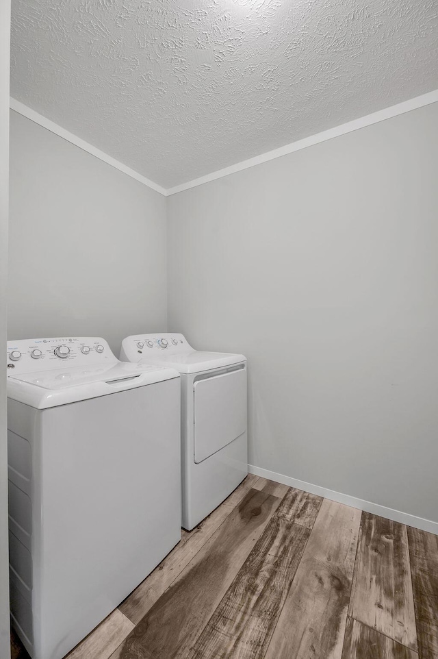 clothes washing area featuring hardwood / wood-style flooring, washing machine and dryer, and a textured ceiling