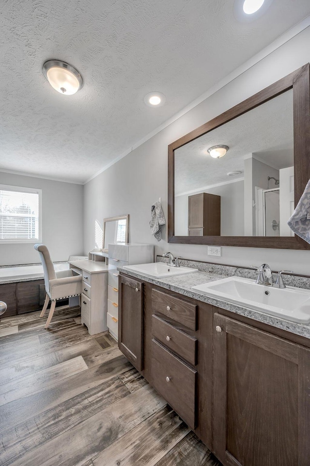 bathroom featuring vanity, hardwood / wood-style flooring, ornamental molding, shower with separate bathtub, and a textured ceiling