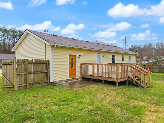 rear view of house featuring a yard, a patio, and a wooden deck