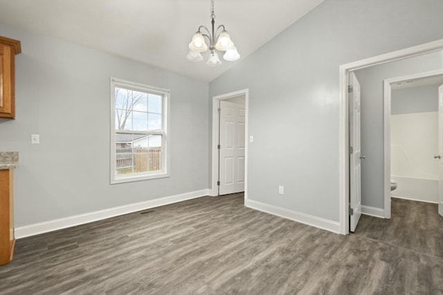 unfurnished dining area featuring dark hardwood / wood-style floors, vaulted ceiling, and an inviting chandelier