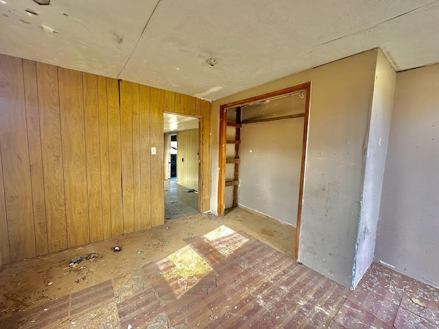 unfurnished bedroom featuring wooden walls and a closet