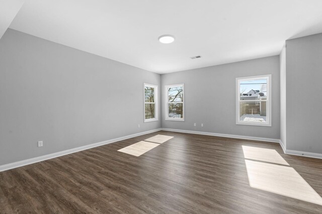 unfurnished living room with dark wood-style floors, visible vents, and baseboards