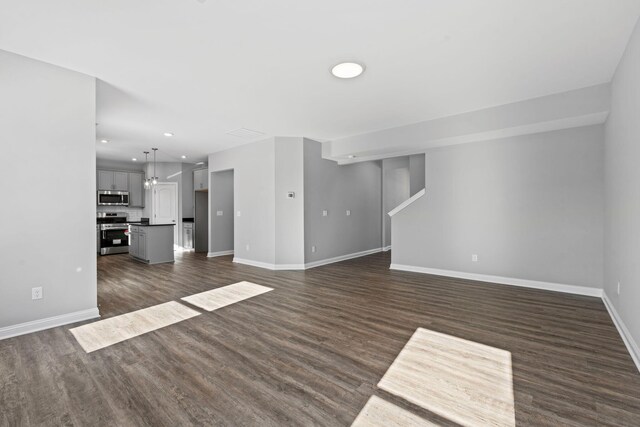 kitchen with dark countertops, appliances with stainless steel finishes, a center island, gray cabinetry, and a sink