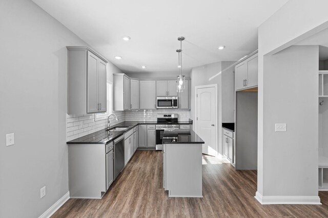 kitchen with stainless steel appliances, tasteful backsplash, a sink, and dark wood finished floors