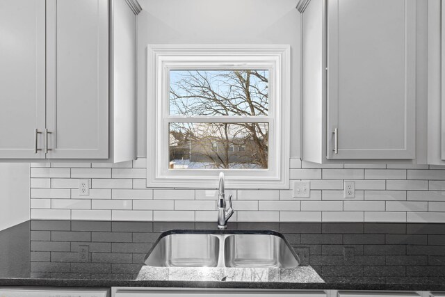 interior details featuring dark stone counters, backsplash, and a sink