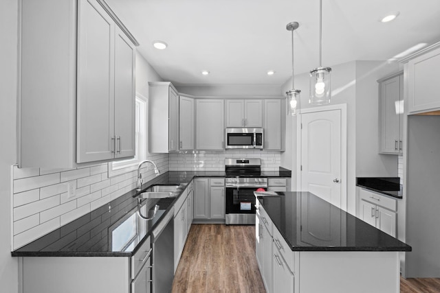 kitchen with tasteful backsplash, a sink, stainless steel appliances, a kitchen island, and dark wood-type flooring
