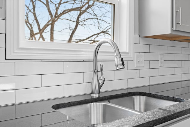 room details featuring dark stone countertops, backsplash, and a sink