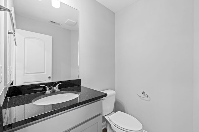 half bathroom with visible vents, toilet, vanity, and baseboards