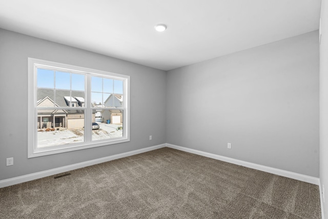 empty room with dark colored carpet, visible vents, and baseboards