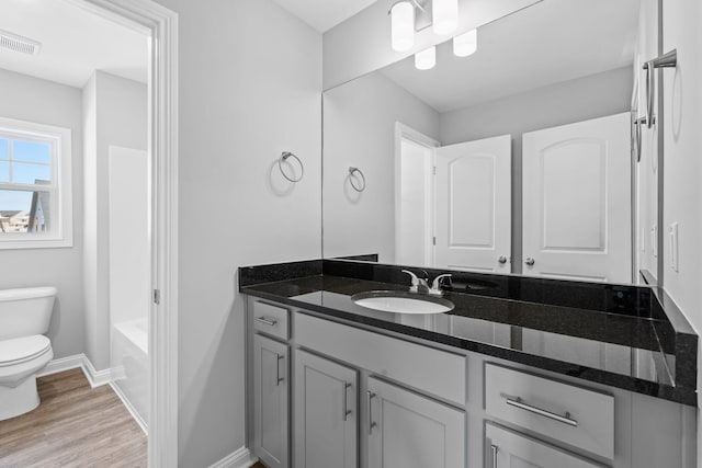 full bath featuring vanity, toilet, visible vents, baseboards, and wood finished floors
