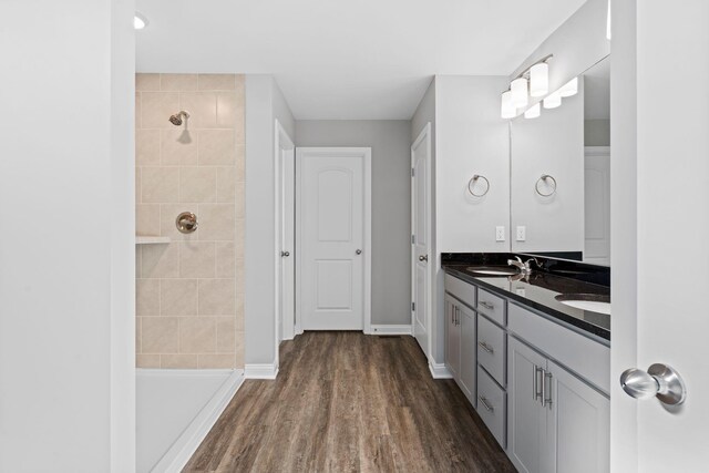 bathroom with wood finished floors, visible vents, a sink, and tiled shower