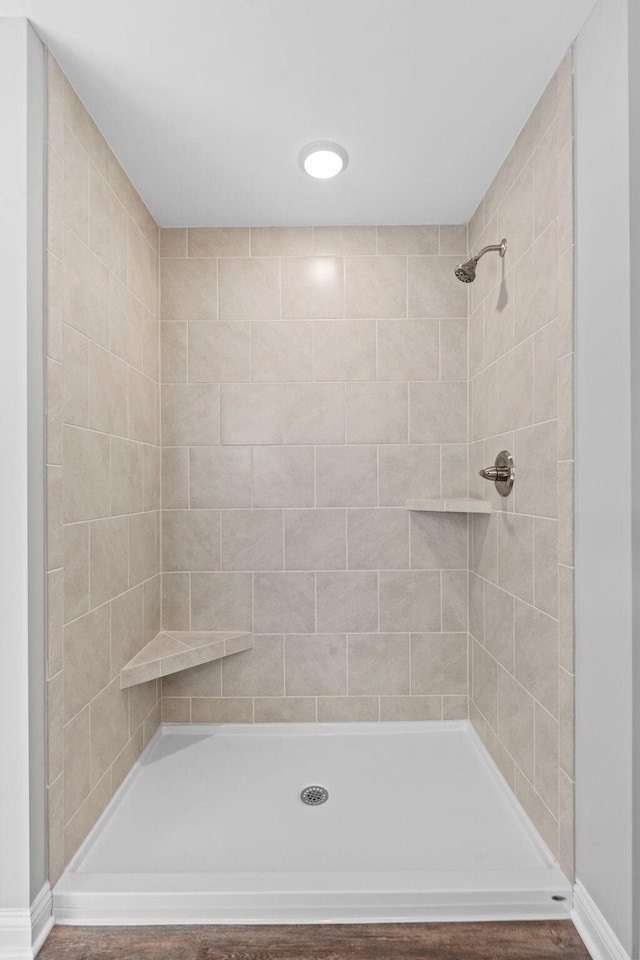 full bath with a tile shower and baseboards