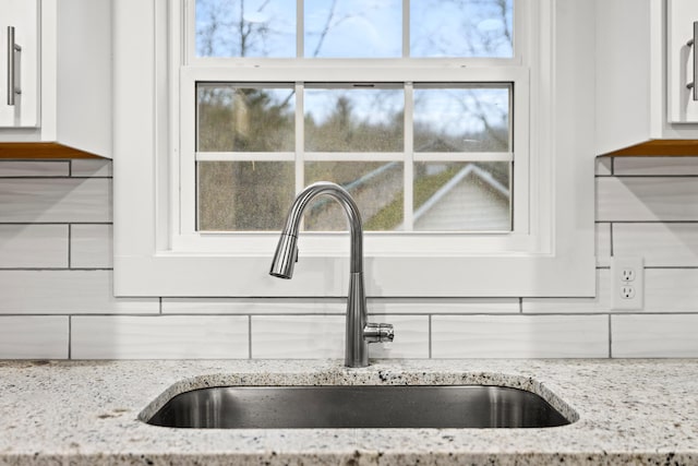 details with light stone countertops, tasteful backsplash, white cabinets, and sink