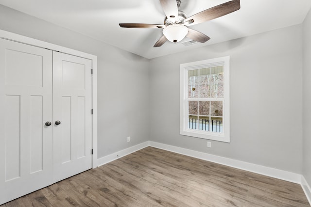 unfurnished bedroom with ceiling fan, light wood-type flooring, and a closet