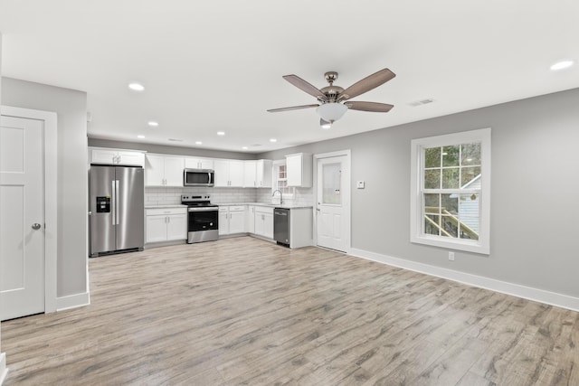 kitchen with white cabinetry, sink, stainless steel appliances, tasteful backsplash, and light hardwood / wood-style floors