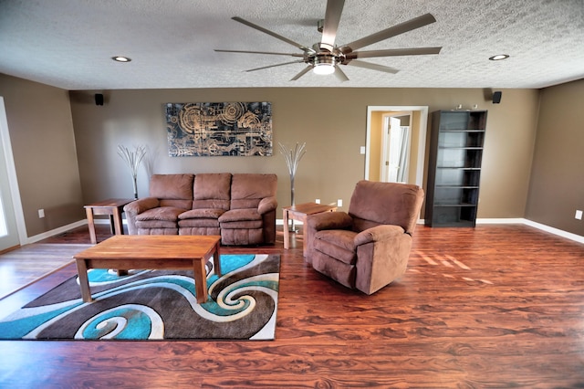 living room with ceiling fan, a textured ceiling, and dark wood-type flooring