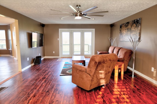 living room featuring a textured ceiling, ceiling fan, and dark wood-type flooring