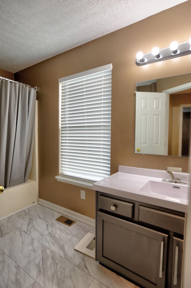 bathroom with shower / bath combo, a textured ceiling, and vanity