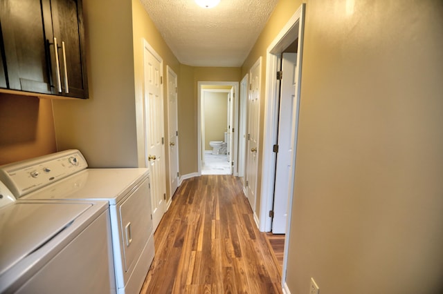 laundry area featuring washer and dryer, hardwood / wood-style floors, cabinets, and a textured ceiling