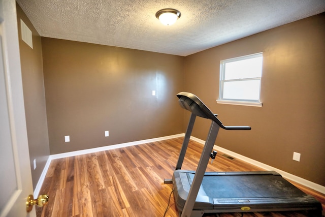 exercise room featuring wood-type flooring and a textured ceiling