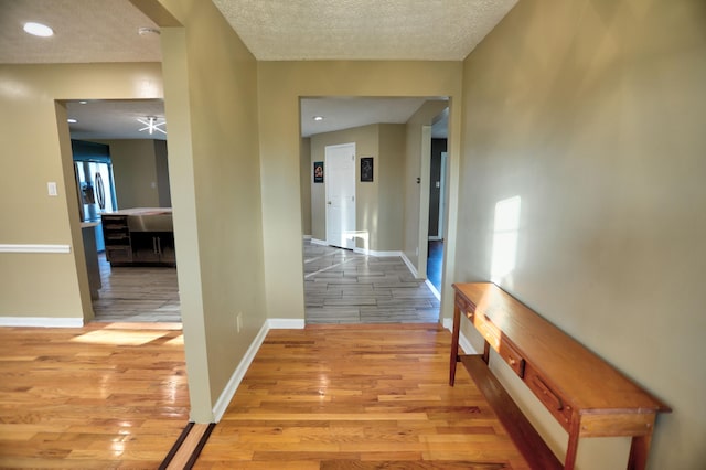 corridor featuring light hardwood / wood-style floors and a textured ceiling