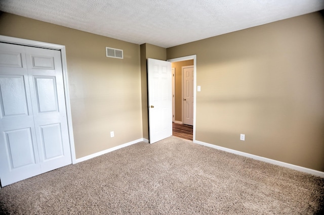 unfurnished bedroom with a textured ceiling, carpet floors, and a closet