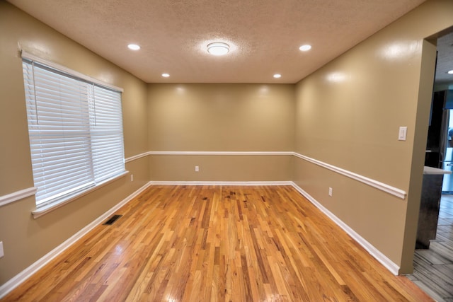 unfurnished room featuring a textured ceiling and light hardwood / wood-style flooring