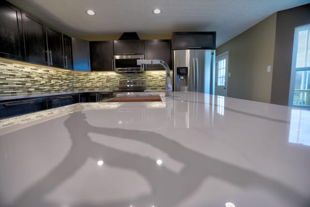 kitchen featuring backsplash, sink, appliances with stainless steel finishes, dark brown cabinets, and light stone counters