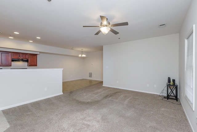 unfurnished living room featuring ceiling fan with notable chandelier and light colored carpet