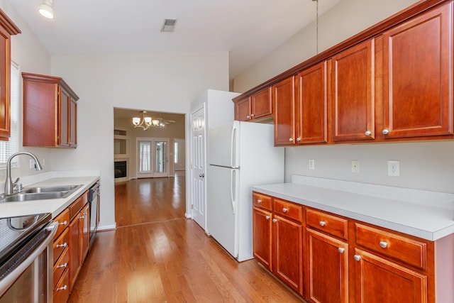 kitchen with white fridge, dishwasher, a chandelier, light hardwood / wood-style flooring, and sink