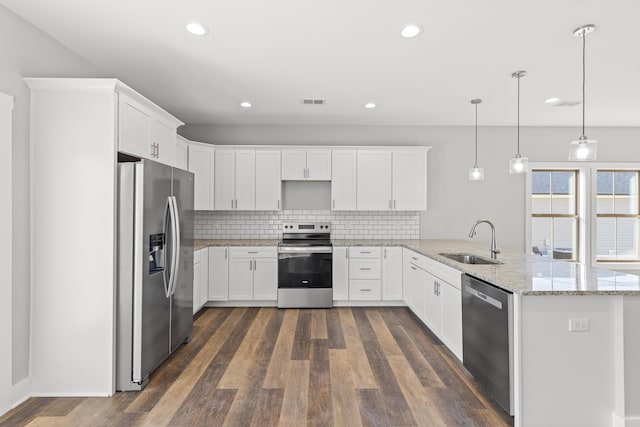 kitchen with white cabinetry, hanging light fixtures, backsplash, kitchen peninsula, and appliances with stainless steel finishes