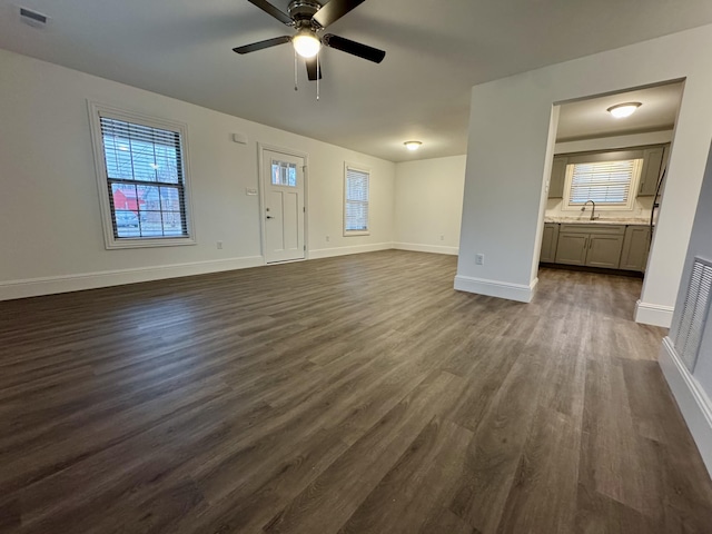 unfurnished living room with sink, dark hardwood / wood-style flooring, plenty of natural light, and ceiling fan