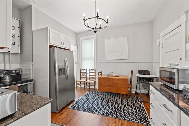 kitchen with stainless steel appliances, pendant lighting, light hardwood / wood-style flooring, a notable chandelier, and white cabinetry