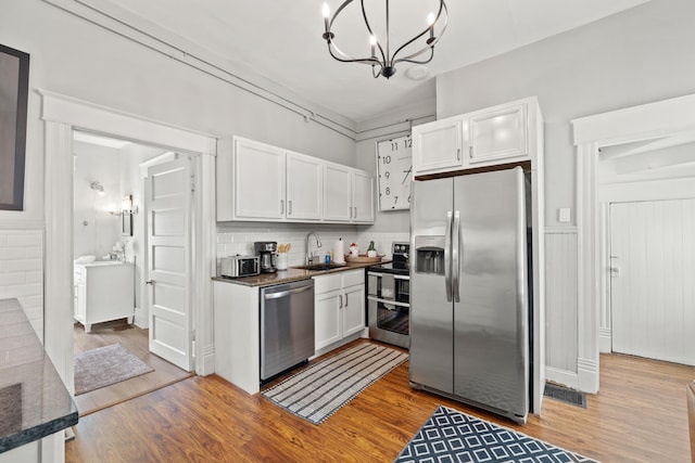 kitchen featuring decorative light fixtures, stainless steel appliances, white cabinetry, and sink