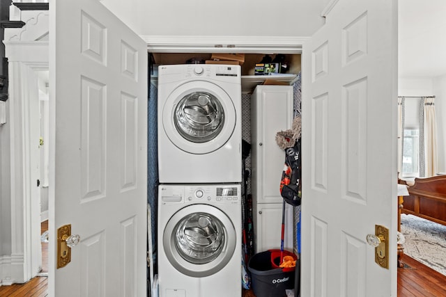 laundry area with cabinets and stacked washing maching and dryer