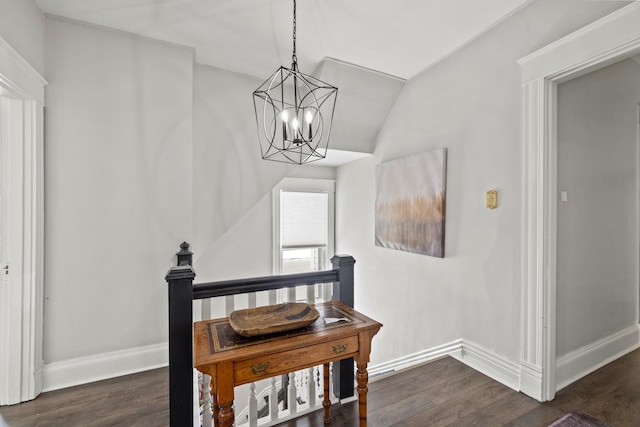 hall with an inviting chandelier, vaulted ceiling, and dark wood-type flooring