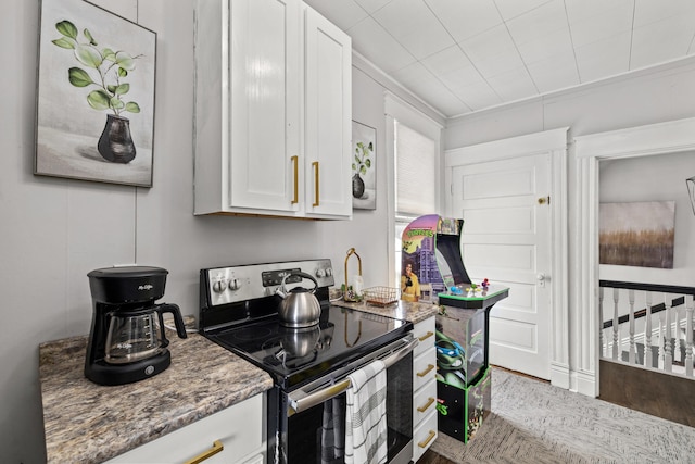 kitchen featuring white cabinetry, dark stone counters, stainless steel range with electric stovetop, and ornamental molding