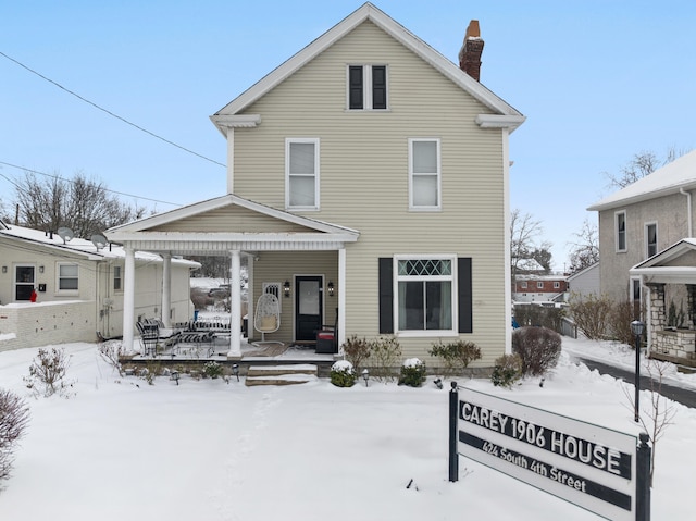 snow covered rear of property featuring covered porch