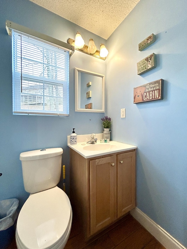 bathroom with vanity, toilet, and a textured ceiling