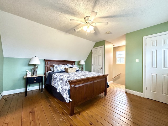 bedroom featuring hardwood / wood-style floors, ceiling fan, lofted ceiling, and a textured ceiling