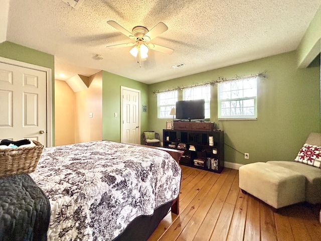 bedroom with ceiling fan, hardwood / wood-style floors, and a textured ceiling