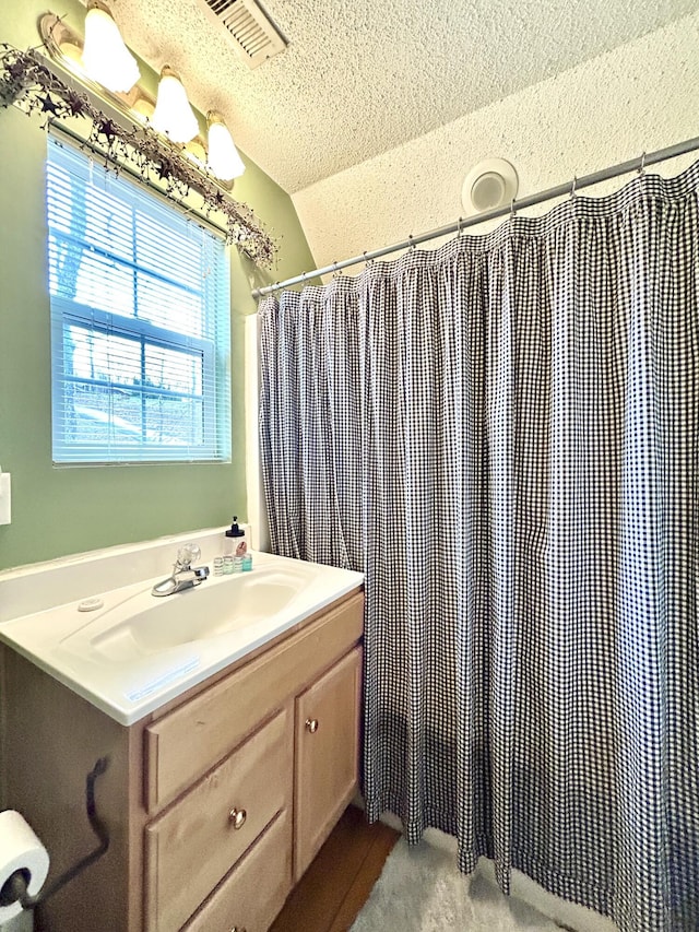 bathroom with vanity, curtained shower, a textured ceiling, and vaulted ceiling