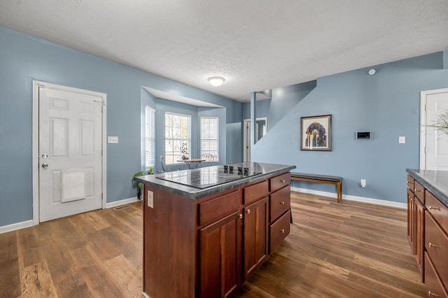 kitchen with dark wood-style floors, dark countertops, black electric cooktop, and a center island