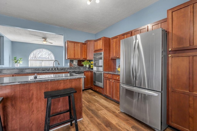 kitchen featuring appliances with stainless steel finishes, dark countertops, a sink, and a breakfast bar