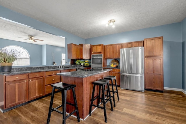 kitchen featuring appliances with stainless steel finishes, a breakfast bar, a center island, and dark countertops